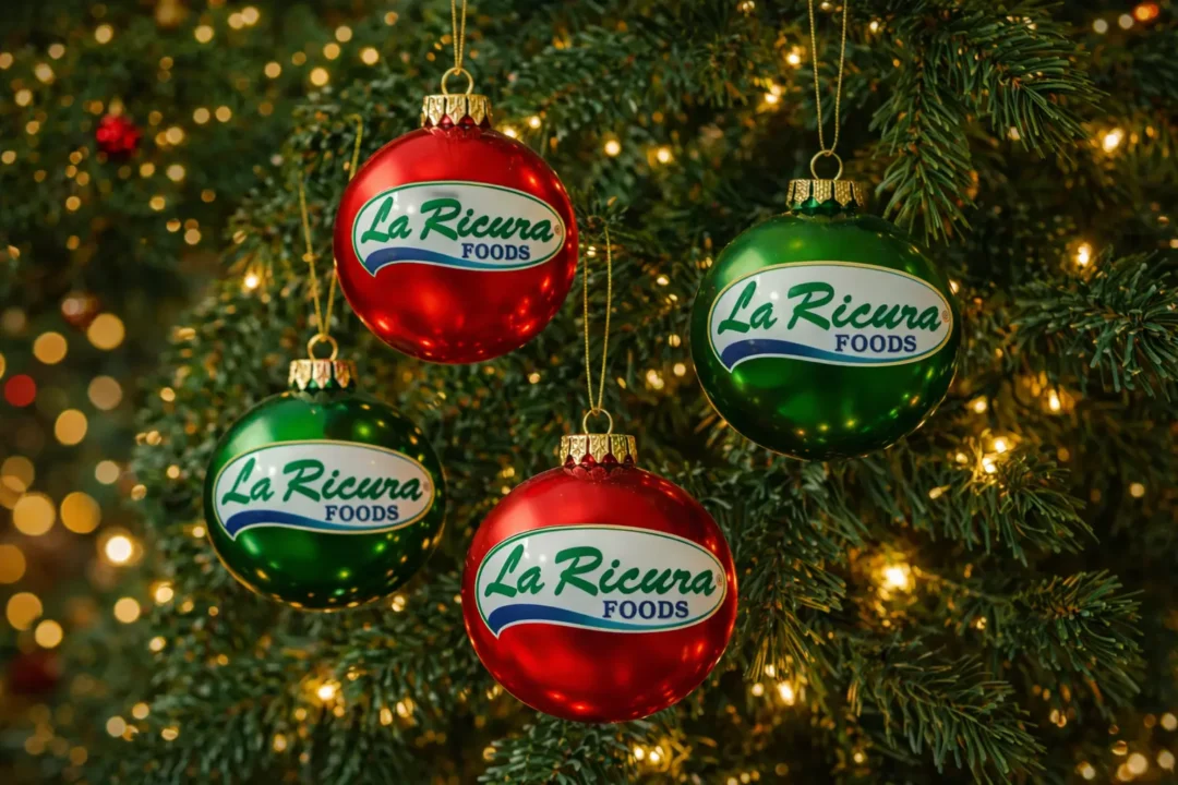 Árbol de Navidad decorado con esferas navideñas que llevan el logo de La Ricura Foods, en un ambiente festivo y tradicional.